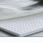 A sheet of white dimpled coremat core material laid between layers of fiberglass