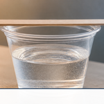 A cup of freshly mixed clear epoxy resin on a workbench with a stir stick