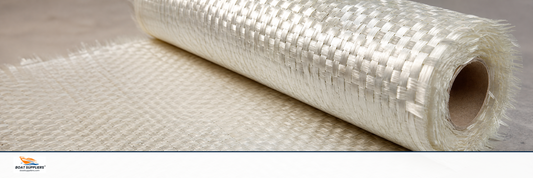 A roll of woven roving fiberglass fabric on a workbench