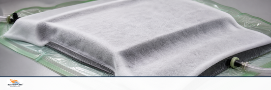White fluffy breather cloth laid over a composite part during vacuum bagging