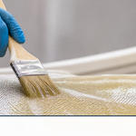 Amber vinyl ester resin being brushed onto woven fiberglass cloth on a hull
