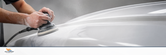 An orbital sander smoothing a glossy white fiberglass hull to a mirror finish