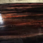Freshly reglassed surfboard deck with deep tinted epoxy gloss finish