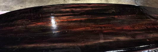 Freshly reglassed surfboard deck with deep tinted epoxy gloss finish