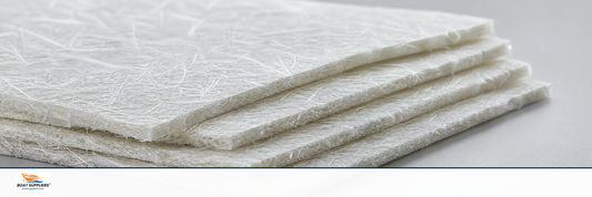 Stacked layers of white chopped strand mat fiberglass on a workbench