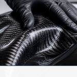 Black carbon fiber twill fabric being laid into a glossy mold