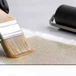A brush saturating woven fiberglass cloth with clear resin until it turns translucent