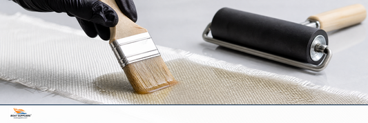 A brush saturating woven fiberglass cloth with clear resin until it turns translucent
