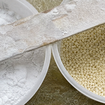 Two mixing cups side by side, one of fluffy white cabosil fumed silica and one of tan microballoons, with a powder-dusted mixing stick across both