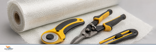 Fiberglass cutting tools including a rotary cutter and shears on a roll of cloth