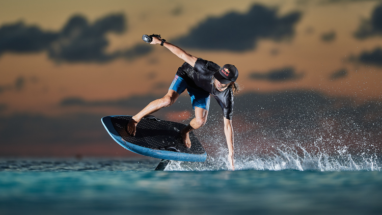 Rider on an eFoil board carving across the water at dusk, watersports gear collection