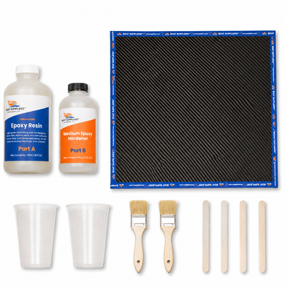 Carbon fiber patch kit contents: 12 inch square of 2x2 twill carbon fiber with blue taped edges, Boat Suppliers two-part epoxy resin and hardener bottles, graduated mixing cups, chip brushes and stir sticks