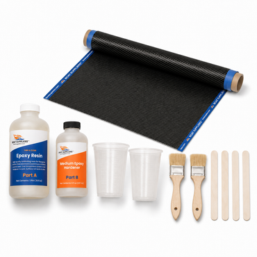Carbon fiber skinning kit contents: 6 inch by 5 foot narrow strip of 2x2 twill carbon fiber with blue taped edges rolled on a tube, Boat Suppliers two-part epoxy resin and hardener bottles, graduated mixing cups, chip brushes and stir sticks