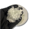 Black-gloved hand holding a handful of chopped strand fiberglass over a tub, loose white E-glass fiber bundles for mixing into resin