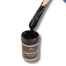 Carbon Black liquid pigment dripping off a stir stick into the open 1 oz jar, glossy opaque marine-grade colorant for resin and gelcoat.