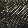 Close-up of the wound edge of a 19.7 oz 12K 2x2 twill carbon fiber roll, stacked fabric layers at left and glossy twill weave across the roll