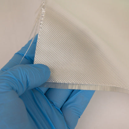 Gloved hand holding the cut edge of satin weave fiberglass cloth